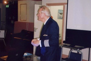 Picture of the speaker wearing a captains uniform.