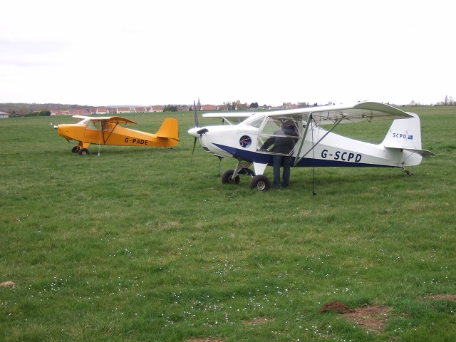 A yellow and white Escapade aircraft parked on grass.