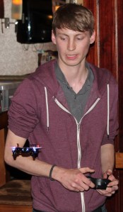 A young man controling a small quadcopter that is hovering in front of him.