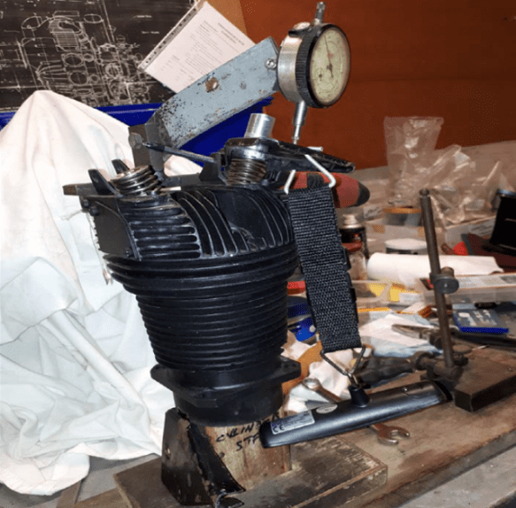 A Pobjoy finned cylinder in a test rig with a digital load measuring tool and a dial test indicator.