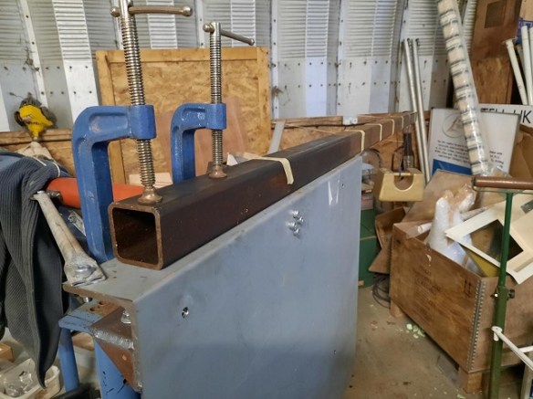 A heavy metal tube attached to a metal plate with two g-clamps.