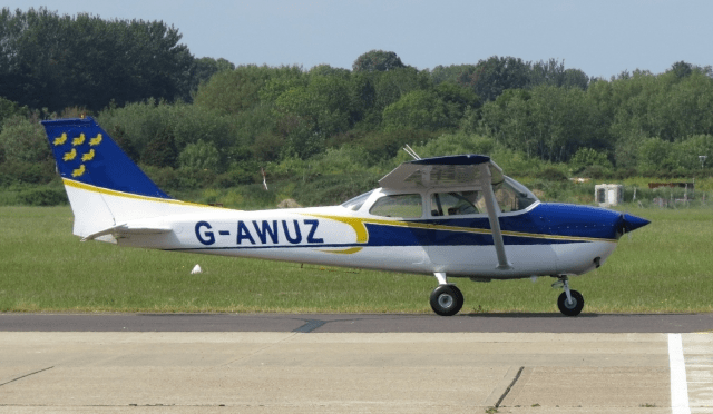 Side view of a taxiing Cessna C172 showing it's white, blue and yellow livery, with the Sussex flag martlets on its tail. 